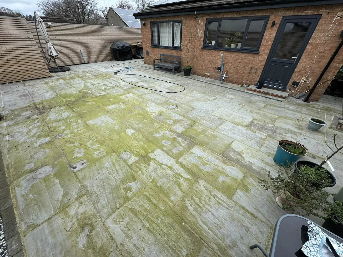 A Thirsk patio before cleaning, slabs covered in green algae
